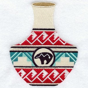 Puede incluir: Un jarrón de cerámica con un patrón geométrico en rojo, blanco y azul. El jarrón tiene un cuello estrecho y una base ancha. Un oso estilizado se encuentra en el centro del jarrón.