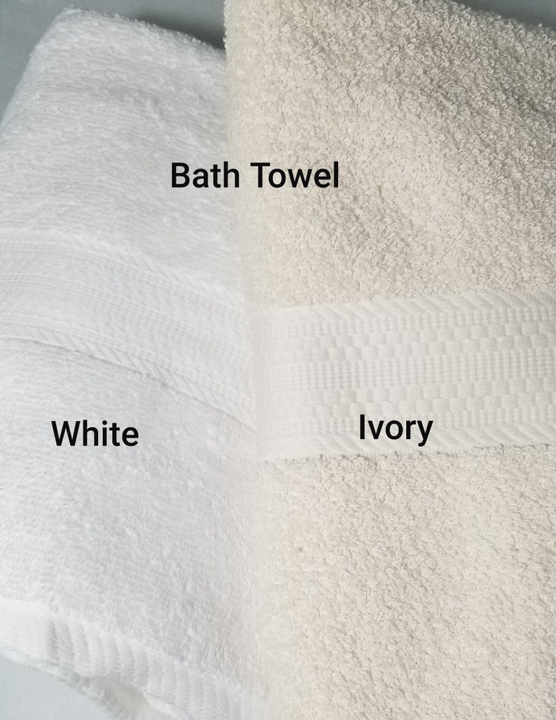 May include: Two bath towels, one white and one ivory. The towels are folded and have a woven border. The text "Bath Towel" is written above the towels, and the words "White" and "Ivory" are written below the towels.