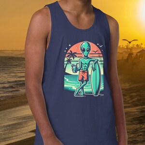 May include: A navy blue tank top with a graphic of a green alien holding a drink and a surfboard on a beach with a sunset in the background.
