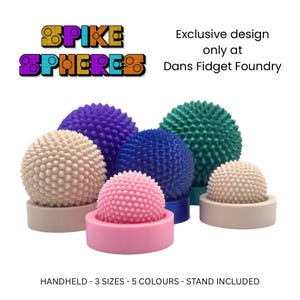May include: A selection of spiky spheres in shades of pink, beige, blue, purple, and teal. Each sphere is mounted on a matching base. The image includes text that reads "SPIKE SPHERES" and "Exclusive design only at Dans Fidget Foundry."