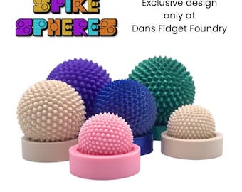 Puede incluir: Esferas espinosas de varios colores, incluyendo rosa, beige, azul, morado y turquesa. Cada esfera está sobre una base a juego. La imagen incluye texto que dice "SPIKE SPHERES" y "Exclusive design only at Dans Fidget Foundry."