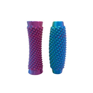 Op de afbeelding: Twee getextureerde, cilindrische objecten. Eén is een verloop van paars naar roze, de andere van blauw naar groen. Beide hebben een herhalend, stekelig patroon. De objecten staan rechtop tegen een witte achtergrond.