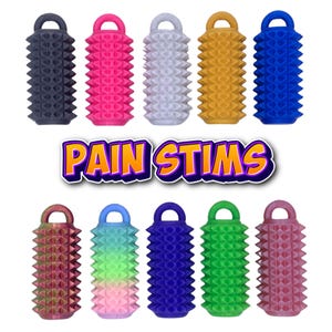 May include: A selection of vibrantly coloured massage tools with a spiked design, in shades such as black, pink, white, yellow, and blue. The text "PAIN STIMS" is displayed in a purple and yellow font. Each tool has a loop handle.