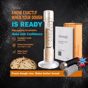 Könnte beinhalten: Ein klarer, zylindrischer Sauerteig-Fermentations-Tracker mit Messmarkierungen von 0 bis 170, ein weißes Anleitungsheft mit der Aufschrift bloomX, eine Holzbox und eine Reinigungsbürste mit schwarzem Griff und grauem, strukturiertem Kopf, neben zwei Brotscheiben.
