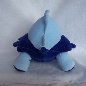 May include: Blue and purple plush toy shaped like a turtle. The turtle has a blue shell and a purple belly.
