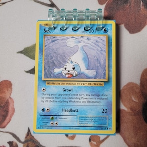 以下が含まれることがあります： 青い毛皮と薄い青色の背景を持つ、シーライオンポケモンが描かれたポケモンカード。カードのタイトルは「シーライオン」で、番号は086。カードには「Growl」と「Headbutt」のテキストと、それぞれの説明が記載されている。