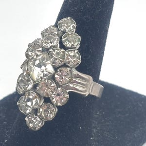 May include: A silver ring with a cluster of clear rhinestones set in a cascading design.