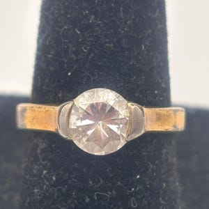May include: A gold ring with a large, clear, round gemstone.