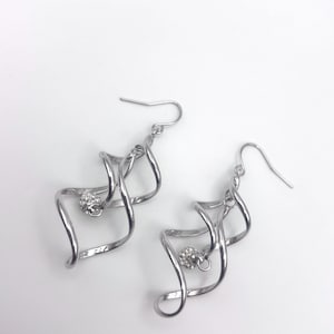 May include: Silver dangle earrings with a twisted design and a small rhinestone embellishment.