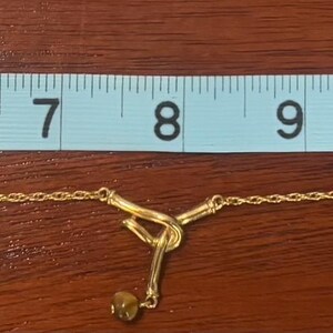 Pu&ograve; includere: Una collana a catena d'oro con un ciondolo a forma di chiave, misurata con un righello, che mostra che &egrave; lunga circa 30 cm.