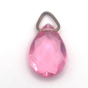 May include: A pink glass teardrop pendant with a gold-toned metal bail.