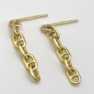 May include: A pair of gold-colored chain link earrings. Each earring features a post for pierced ears and a series of connected links, creating a dangling effect. The earrings are displayed against a white background.