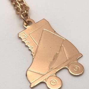 May include: A gold-toned roller skate charm necklace. The charm is detailed with laces and wheels.