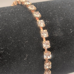 May include: A gold chain bracelet with clear rhinestones.