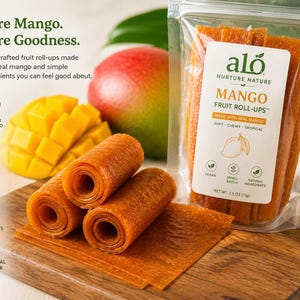 May include: A clear bag of mango fruit roll-ups next to a sliced mango and a whole mango. The bag has a label that reads "Mango Fruit Roll-Ups" and "Made with Real Mango." The roll-ups are orange and appear soft and chewy.