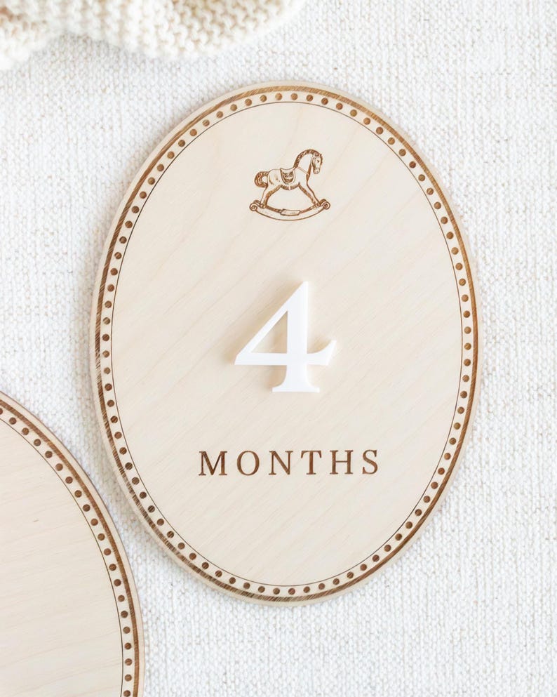 Close-up of engraved wooden baby month milestone plaque with teddy bear artwork and clean neutral finish. Baby monthly photo prop for newborn milestones and infant monthly pictures, used to show baby age 1 month, 2 months, 3 months and beyond. Great for first year photo keepsakes, baby shower gift, neutral nursery decor, wooden month markers, milestone discs/plaques.