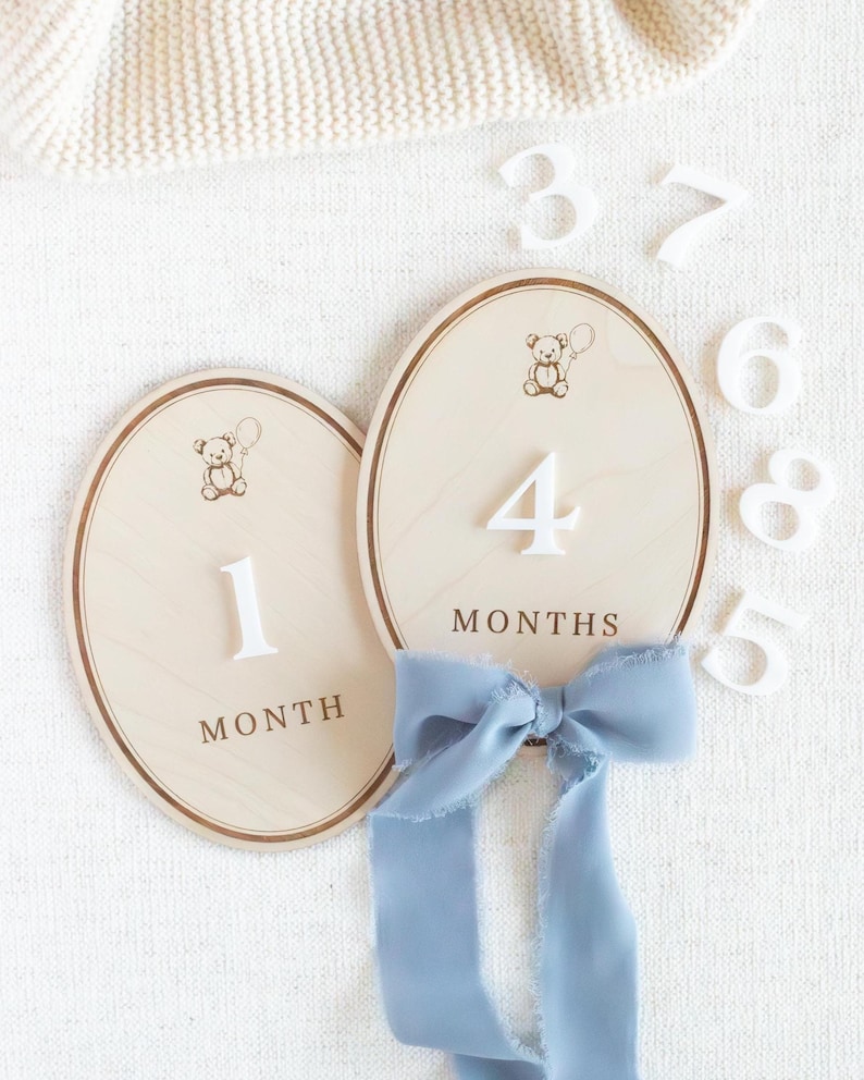 Set of wooden monthly milestone plaques for baby photos, designed to document baby growth from newborn to one year. Baby month markers used in monthly photo sessions, flat lays, and nursery styling. Neutral teddy bear design fits modern nursery decor, baby boy milestone photos, gender neutral baby gifts, handmade wooden milestone discs or plaques.