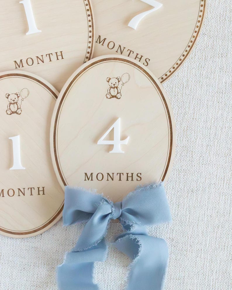 Wooden baby milestone plaques designed for monthly baby photos, featuring a soft neutral teddy bear theme. Used as baby month markers to capture newborn through first year milestones from 1 month to 12 months. Ideal photo prop for infant pictures, baby boy or gender neutral nursery decor, first year baby keepsake, baby shower gift, handmade wooden milestone discs or plaques.