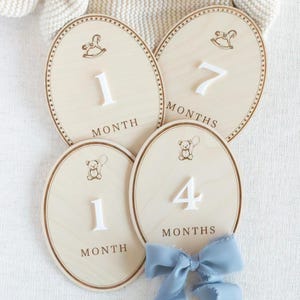 Neutral wooden baby month milestone markers styled for newborn and infant photography. Monthly photo prop used to show baby age progression and growth milestones during the first year. Teddy bear nursery decor works for baby boy or gender neutral nurseries. Popular baby shower gift, first year photo keepsake, wooden milestone plaques for monthly baby pictures.