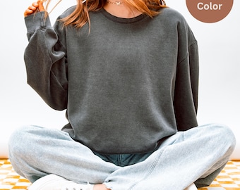 May include: A dark gray, crew neck sweatshirt with a vintage wash effect. The sweatshirt is shown on a person wearing light blue jeans and white sneakers. A circular graphic in the upper right corner reads "Pepper Color."