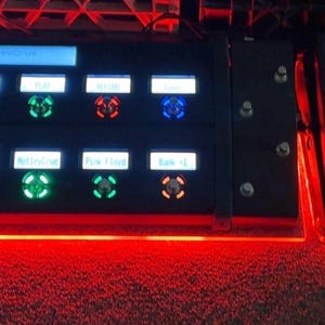 Puede incluir: Un procesador de efectos de guitarra Fractal Audio Systems negro con múltiples botones iluminados y una pantalla. Tres pedales negros están a la derecha, con iluminación roja. La unidad está diseñada para efectos de instrumentos musicales.