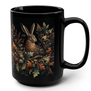 May include: Black ceramic mug with a graphic of a brown rabbit sitting in a bed of colorful autumn leaves and vines.