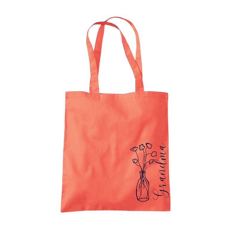 Pu&ograve; includere: Una borsa tote color corallo con testo nero che dice "Nonna" e un semplice disegno a linea di un vaso con fiori.