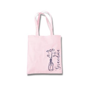 Pu&ograve; includere: Borsa tote rosa con un design floreale e la parola "Nonna" in corsivo.