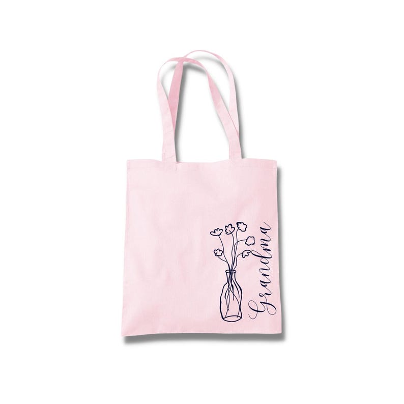 Pu&ograve; includere: Borsa tote rosa con un design floreale e la parola "Nonna" in corsivo.