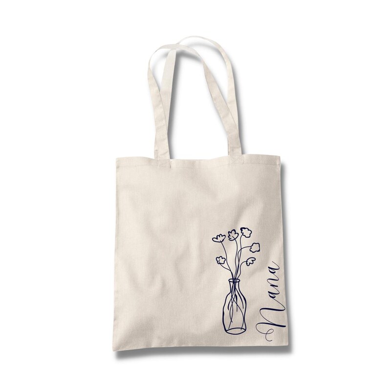 Pu&ograve; includere: Una borsa tote in tela bianca con un disegno a linea blu di un vaso con fiori e la parola "Mama" sul lato.