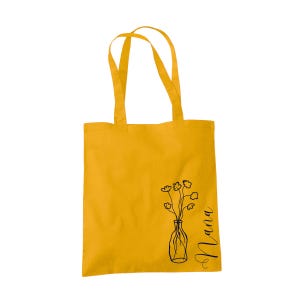 Pu&ograve; includere: Una borsa tote gialla con un disegno a linea nera di un vaso con fiori e la parola "Mama" sul lato.