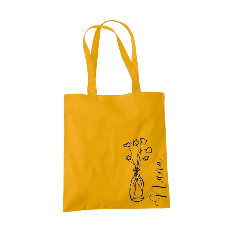 Pu&ograve; includere: Una borsa tote gialla con un disegno a linea nera di un vaso con fiori e la parola "Mama" sul lato.