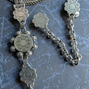 Peut inclure: Collier argent&eacute; avec un motif floral. Le collier est compos&eacute; d'une cha&icirc;ne avec un fermoir en forme de fleur et de pendentifs en forme de fleur. Le fond est un motif de carte.