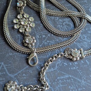 Peut inclure: Collier argent&eacute; avec un pendentif floral et des accents de cristaux transparents. Le collier pr&eacute;sente un motif de cha&icirc;ne tiss&eacute;e et une fermeture &agrave; mousqueton. Le pendentif comporte plusieurs cristaux transparents dispos&eacute;s en forme de fleur.