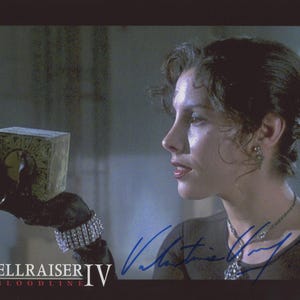 May include: A woman holding a golden puzzle box with intricate carvings. The box is the focal point, held in a gloved hand. The image is from the movie "Hellraiser IV: Bloodline", with the title text at the bottom.