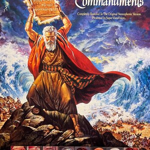 May include: A film poster for the movie "The Ten Commandments" directed by Cecil B. DeMille. The poster features Charlton Heston as Moses holding the Ten Commandments tablets, with a dramatic backdrop of a stormy sea. The poster also includes the names of the main actors, including Yul Brynner, Anne Baxter, Edward G. Robinson, and Yvonne De Carlo.