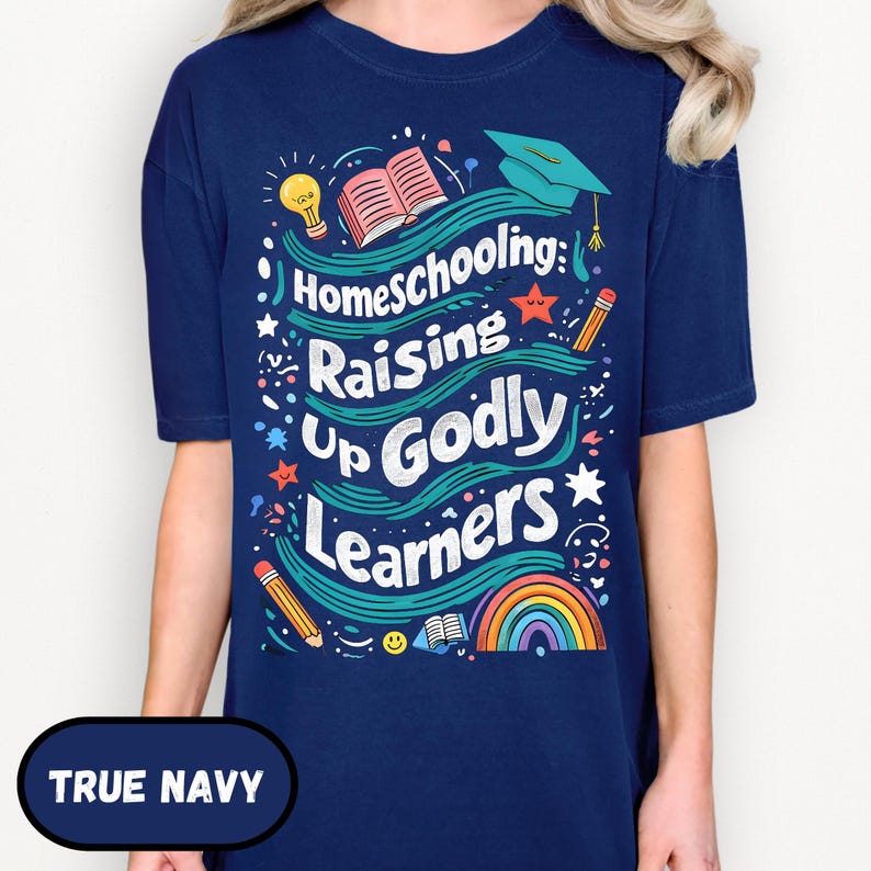 May include: A navy blue t-shirt with the text "Homeschooling: Raising Up Godly Learners" in a colorful design. The design includes a rainbow, pencils, a graduation cap, and an open book.