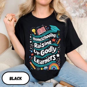 May include: Black t-shirt with the text "Homeschooling: Raising Up Godly Learners" in a colorful design. The design includes a graduation cap, books, pencils, a rainbow, and a lightbulb. The word "BLACK" is in a white oval at the bottom.