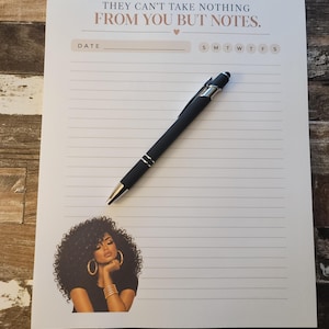 May include: A white lined notepad featuring the text "THEY CAN'T TAKE NOTHING FROM YOU BUT NOTES." at the top, a date line, and a graphic of a person with curly hair at the bottom. A black ballpoint pen with silver accents rests on the paper.