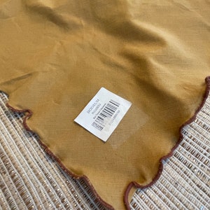 May include: A brown linen tablecloth with a scalloped edge and a brown label that says "BODRUM" and "Rug 162631" with a barcode.
