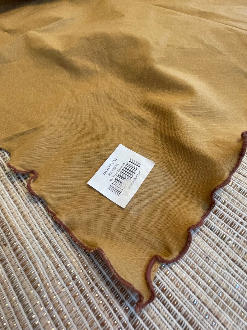 May include: A brown linen tablecloth with a scalloped edge and a brown label that says "BODRUM" and "Rug 162631" with a barcode.