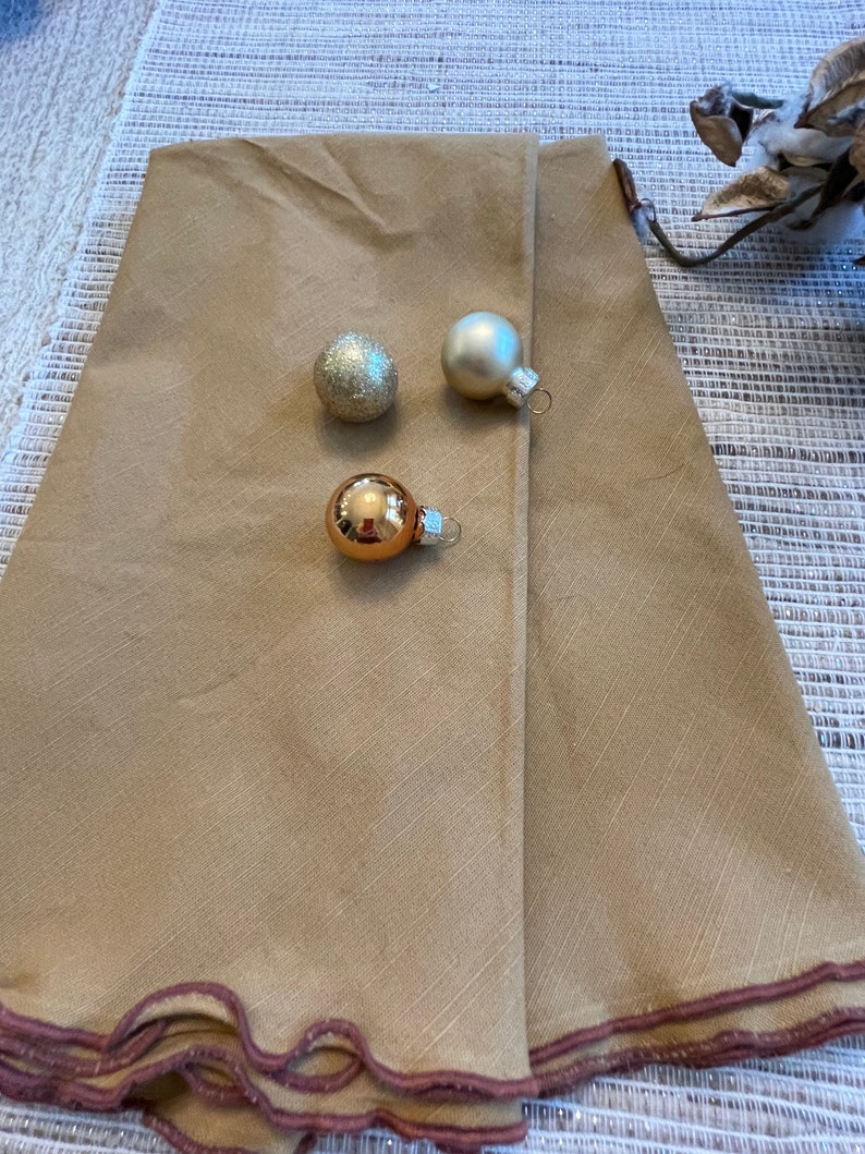 May include: A tan tree skirt with a scalloped edge and three gold and silver ornaments.
