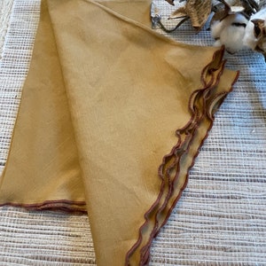 May include: Two folded brown linen napkins with a scalloped edge and a brown trim.