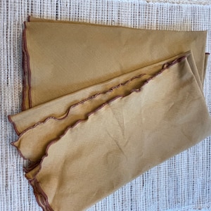 May include: Two brown linen napkins with scalloped edges and a brown embroidered trim.