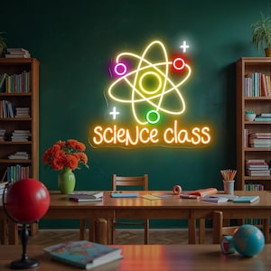 May include: A neon sign in a classroom setting displays a colorful atom symbol with the words "science class" in orange. The sign is mounted on a dark green wall. Bookshelves, a table, and a globe are visible.