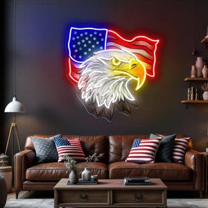 May include: A neon sign depicting an American flag and a bald eagle. The flag is red, white, and blue, and the eagle is white, yellow, and brown. The sign is mounted on a dark gray wall above a brown leather sofa with American flag pillows.