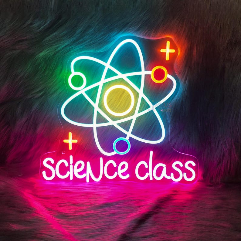 May include: A neon sign in the shape of an atom with the words "science class" in white script. The atom is outlined in white with colorful accents of yellow, blue, green, and orange. The sign glows with a pink and purple hue.