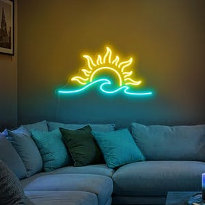 May include: A neon sign depicting a yellow sun setting over blue waves. The sign is mounted on a wall above a blue sofa with cushions.