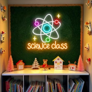 May include: A neon sign with a science theme, featuring an atom symbol and the words "science class" in a bright, glowing font. The sign is mounted on a green textured background. Below, a shelf displays books and decorative items, including miniature houses and a reindeer figurine.