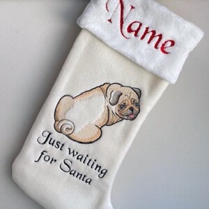 May include: White Christmas stocking with a personalized name, "Name", embroidered on the cuff. The stocking features an embroidered pug with the text "Just waiting for Santa".